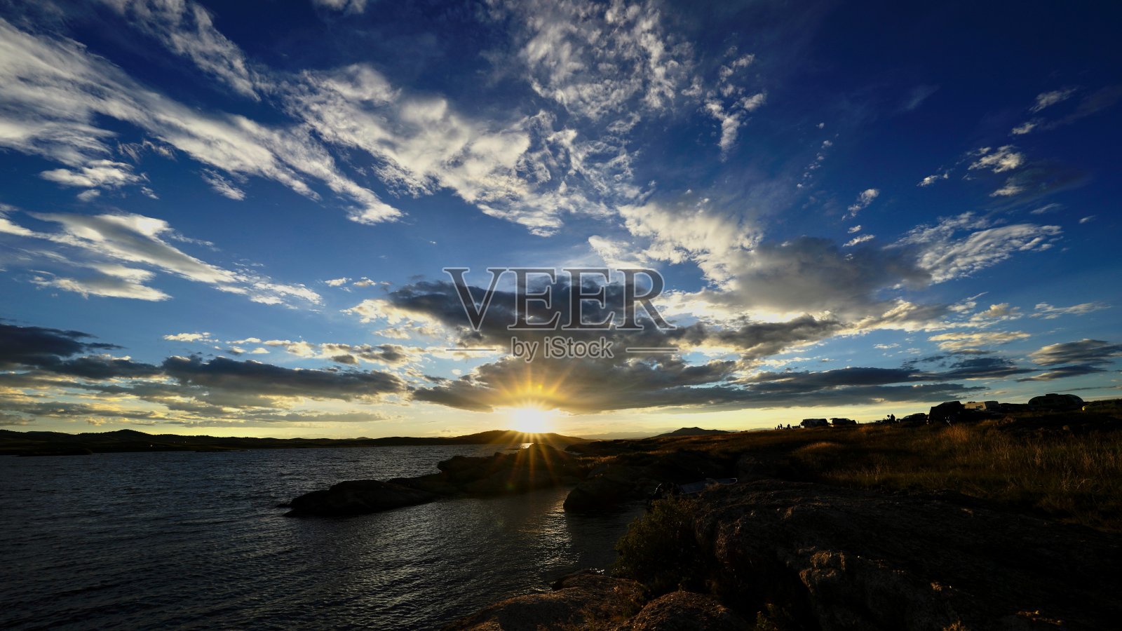 太阳落在乌云笼罩的海面上的景象照片摄影图片