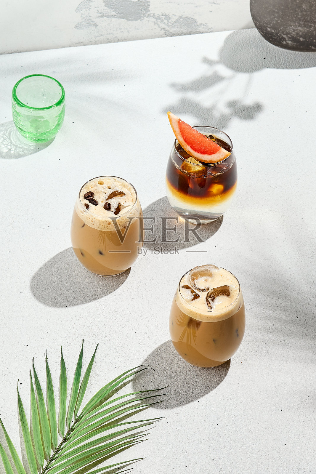 混合冰咖啡在白色混凝土背景与棕榈阴影。搭配夏日冷饮:浓缩咖啡、冰摩卡奇诺和拿铁。夏季咖啡菜单构图。照片摄影图片