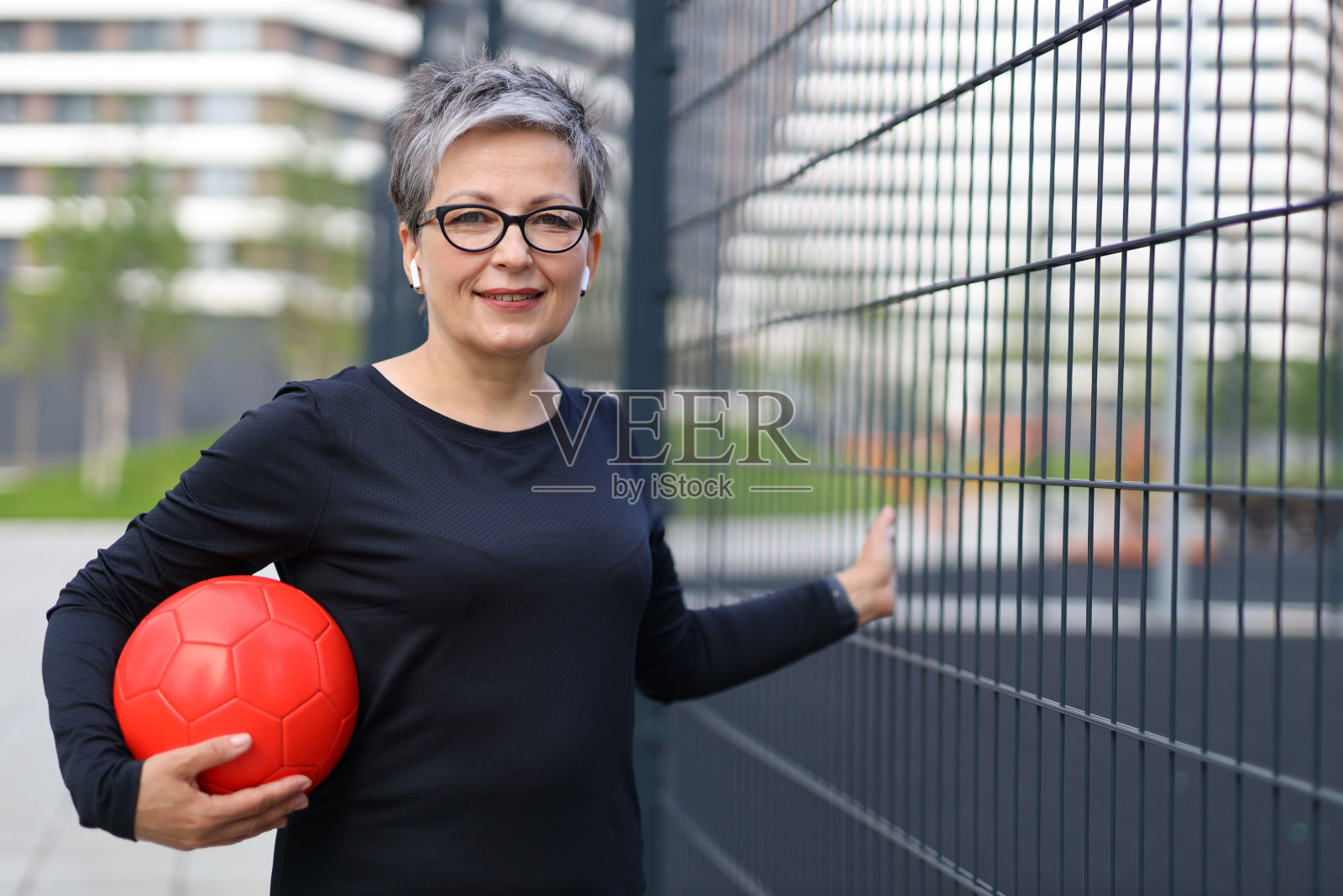一个强壮美丽的成熟女人展示她的健康，在户外用球锻炼，强调力量和平衡的健康生活方式。照片摄影图片