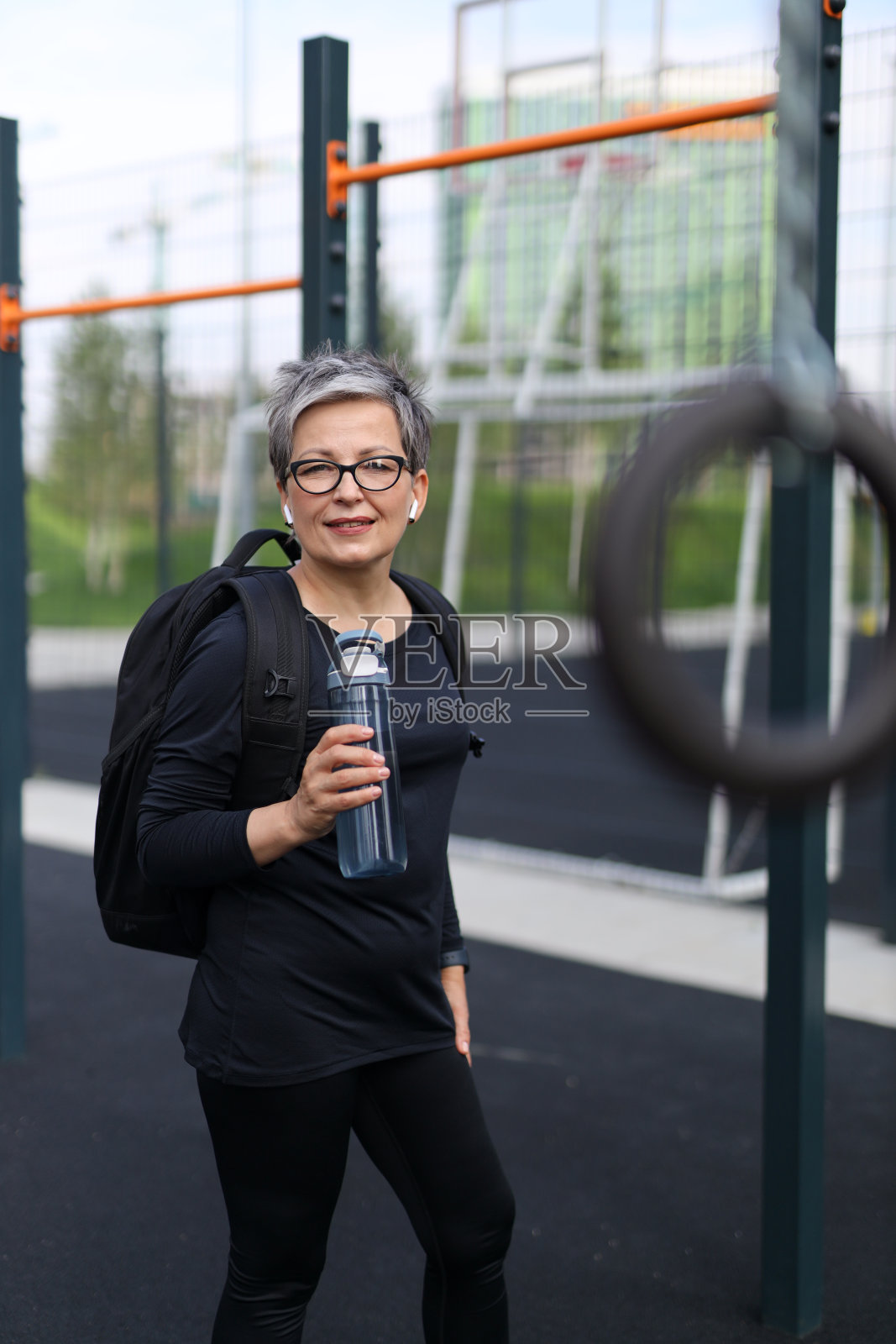 运动的，成熟的女人带着快乐的微笑在户外喝水，在一个以力量为重点的锻炼课程。照片摄影图片