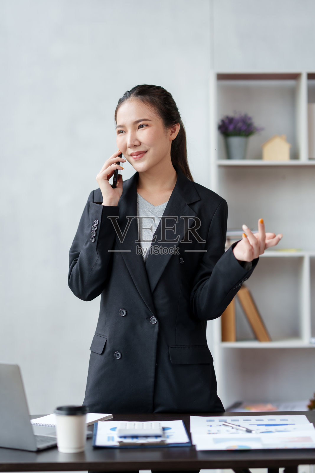 微笑的亚洲女商人享受电话，回答问题，在电话中与客户交谈，并在办公室发表评论。照片摄影图片