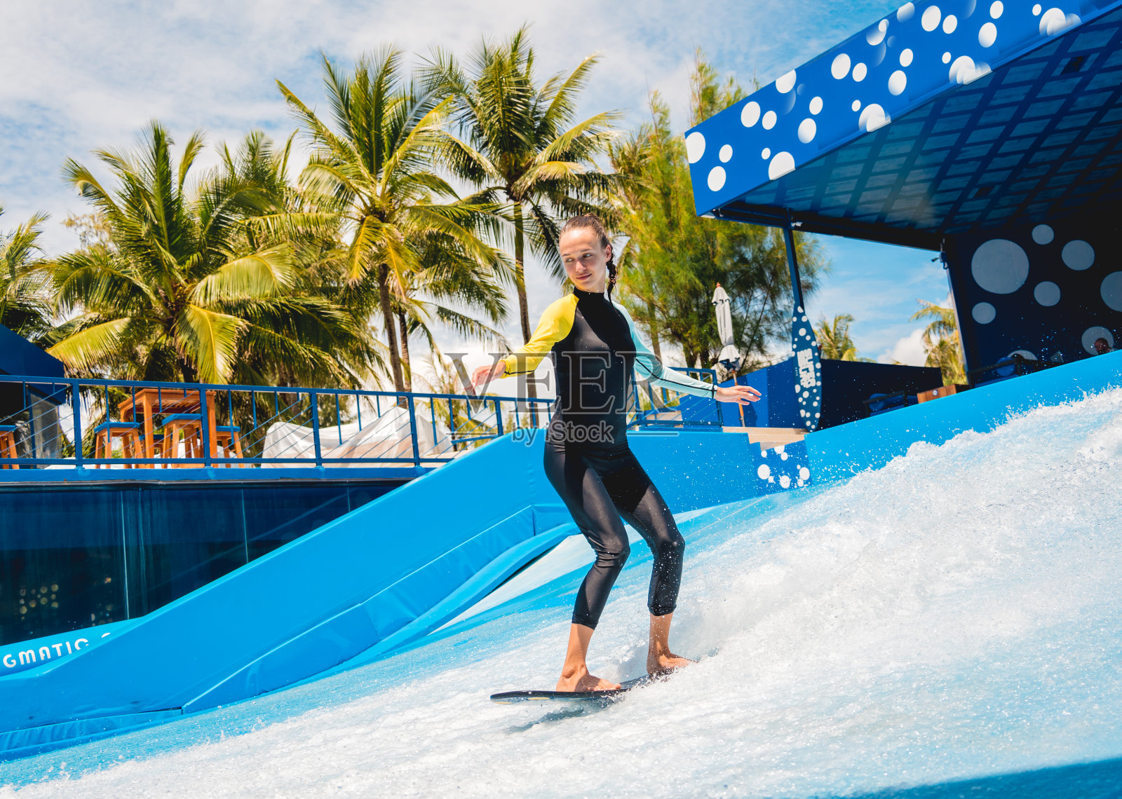 美丽的年轻女子在水上游乐园的波浪模拟器上冲浪照片摄影图片