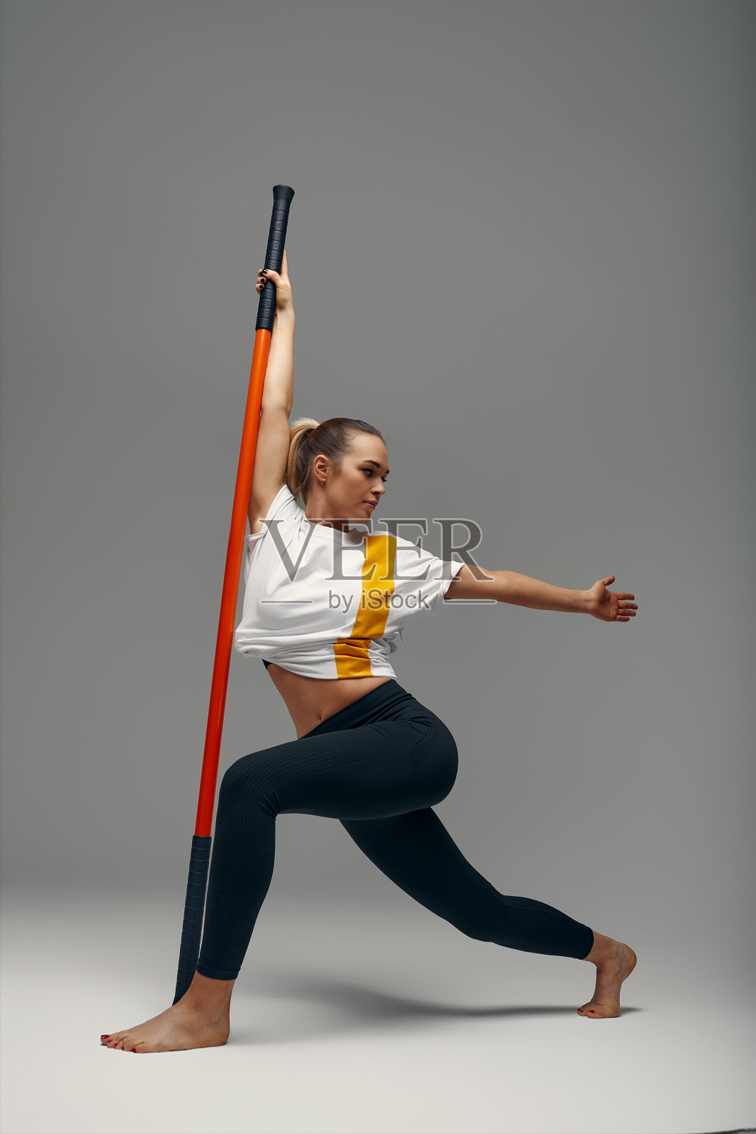 穿着运动服的漂亮女孩正在练功房里练功夫，搏击运动员，用棍子练习武术照片摄影图片