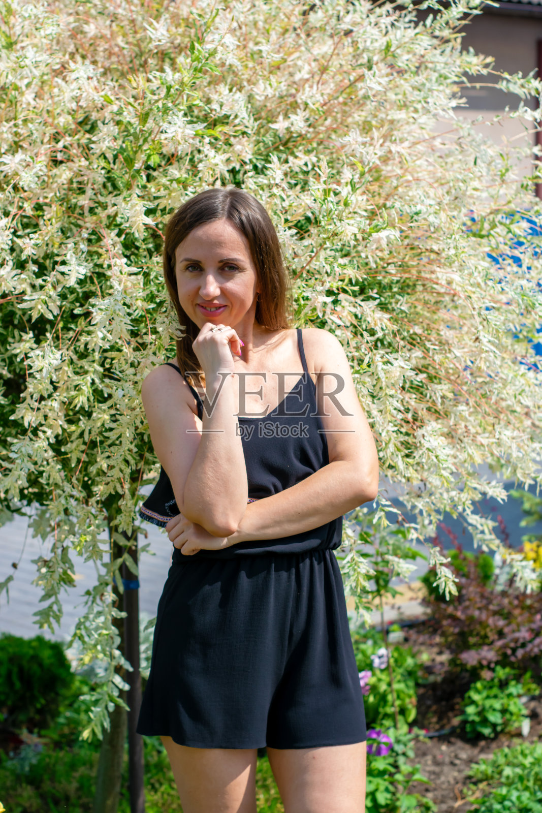 一个穿着黑色浅色衣服的女孩，身后是一棵豪华的白纹锦柳。照片摄影图片