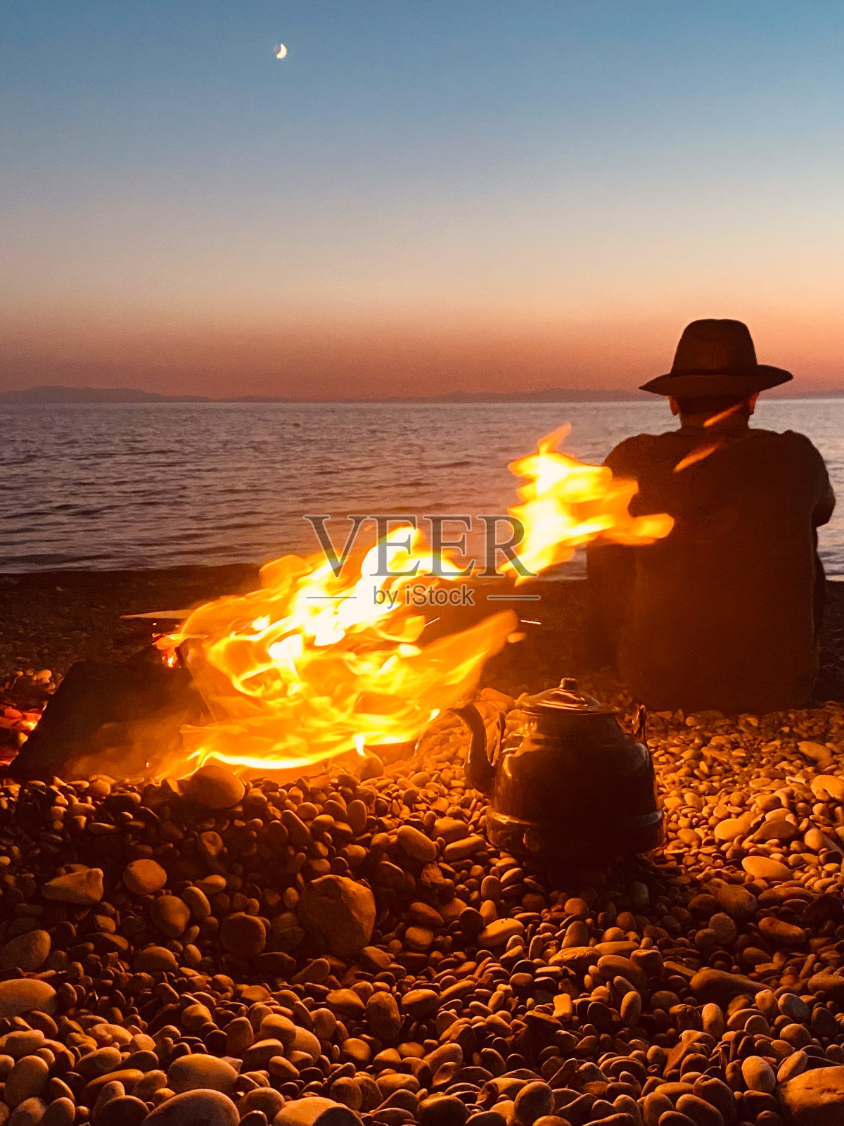 男子在海边生篝火照片摄影图片