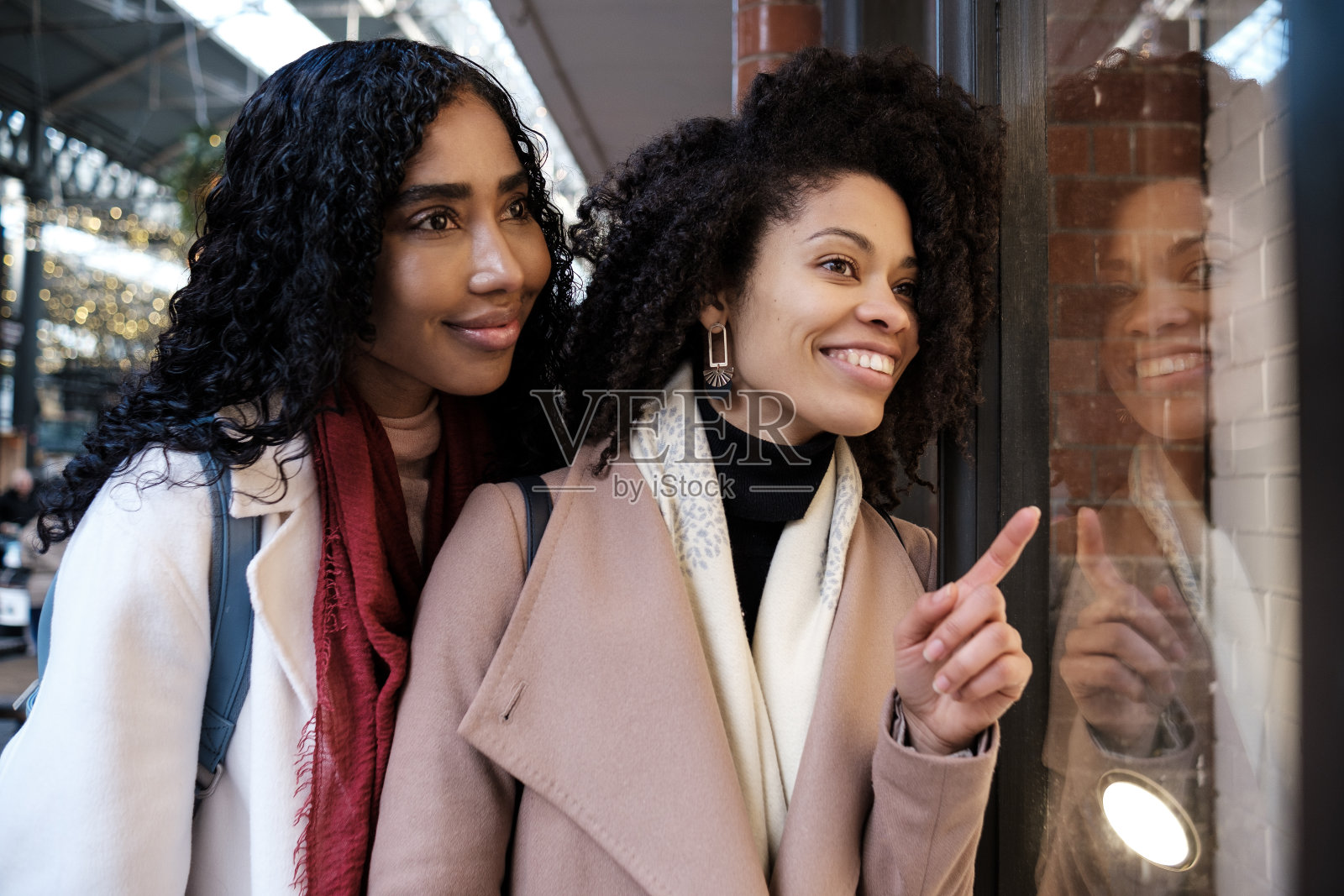 两位女性朋友在商店橱窗前享受购物。照片摄影图片
