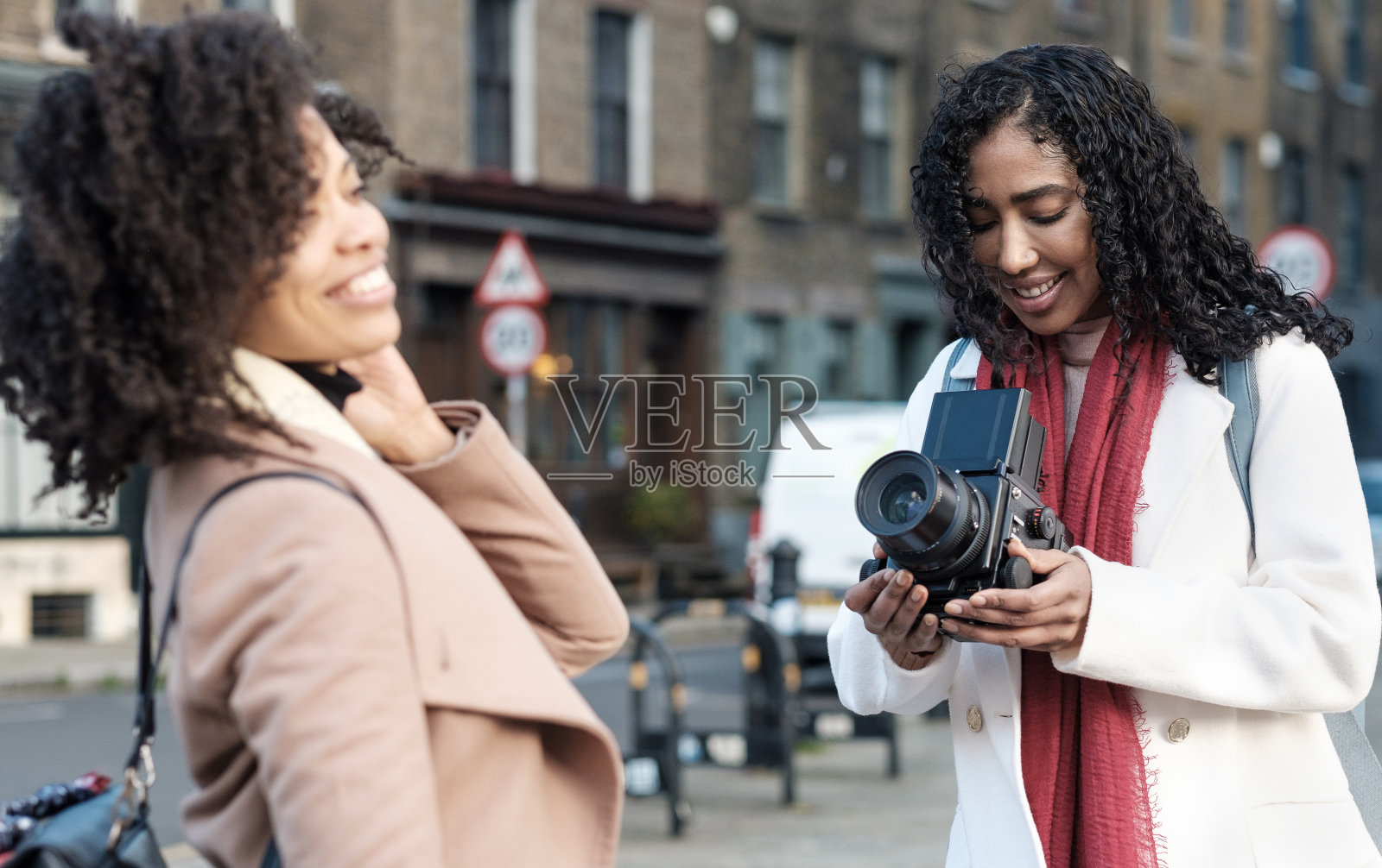 专业女摄影师在街上与女性合影。照片摄影图片