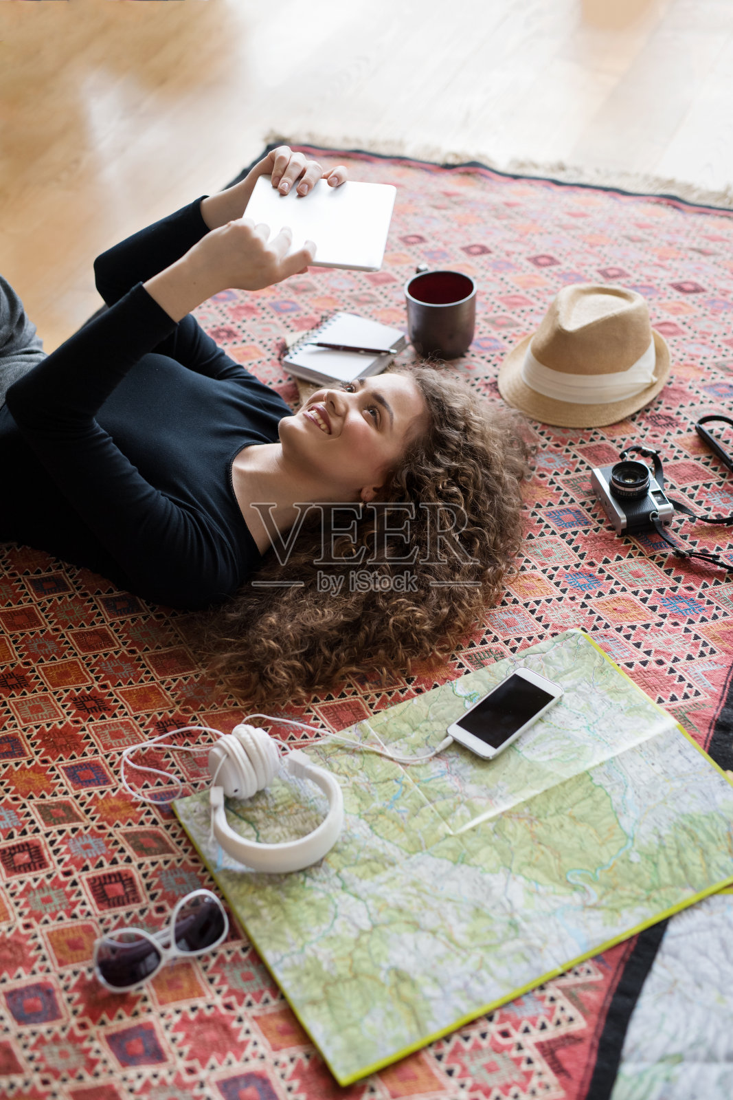 女人计划暑假出国，独自旅行。躺在地毯上，做着冒险的白日梦。照片摄影图片