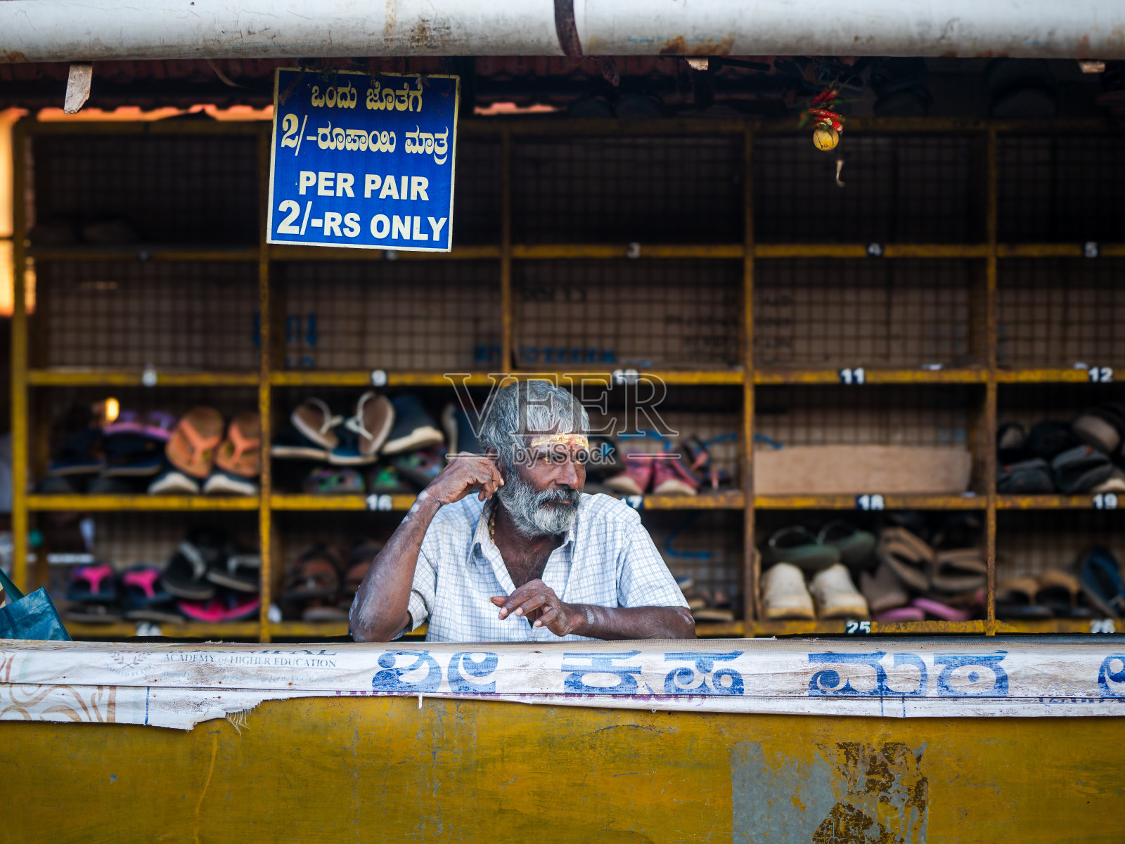 南印度一位白胡子老人站在寺庙外的鞋摊旁照片摄影图片