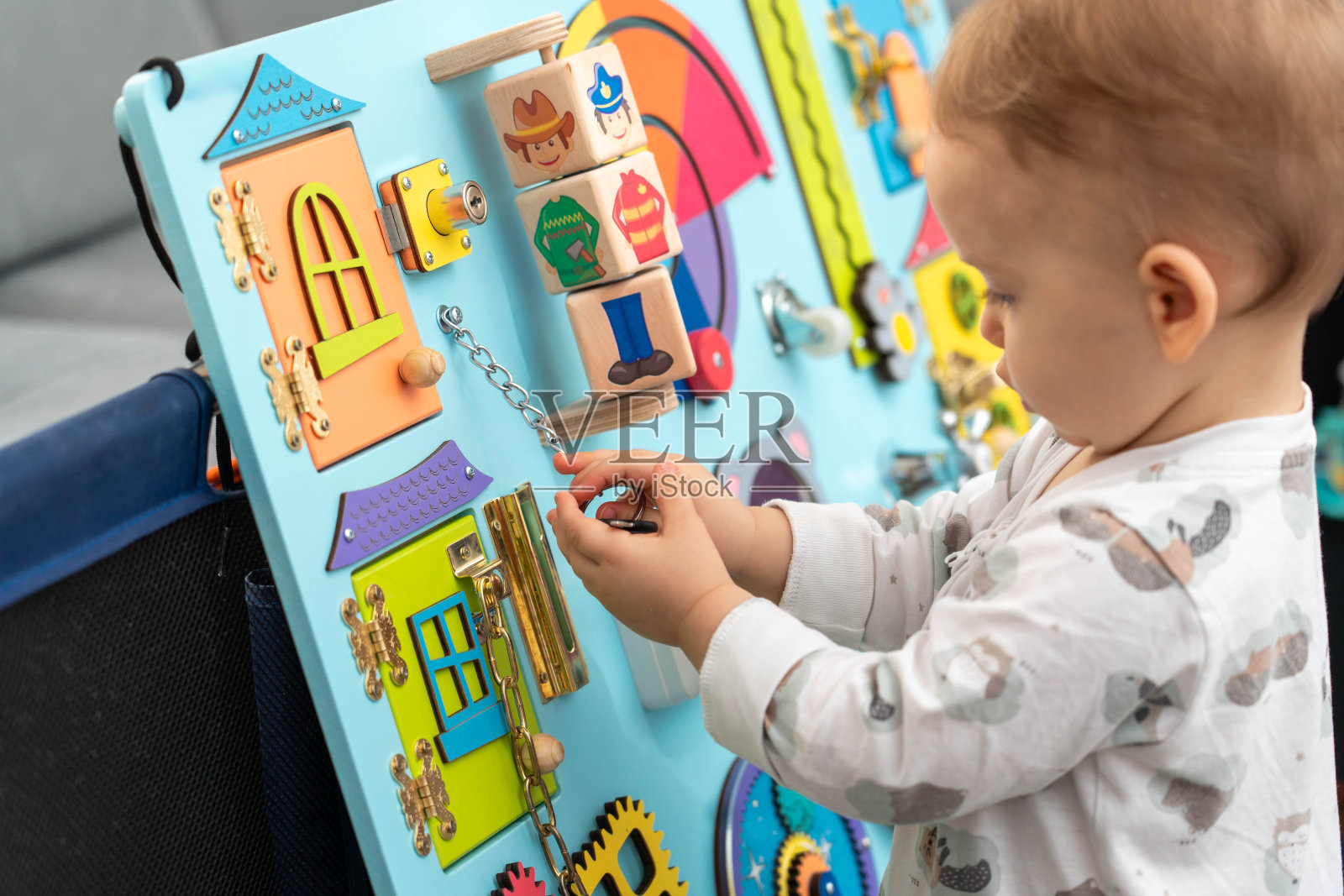 婴儿拿着链子上的钥匙，玩着忙碌的棋盘照片摄影图片