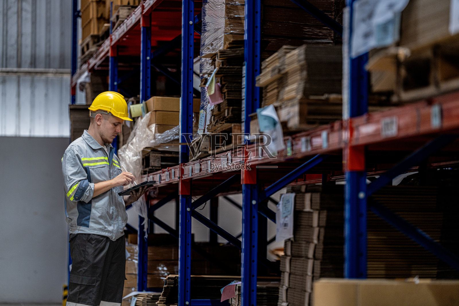 男工人行走和检查库存货物的运输。男在检查工厂的仓库。物流员工在现场仓库区拿着文件夹准备运输。照片摄影图片
