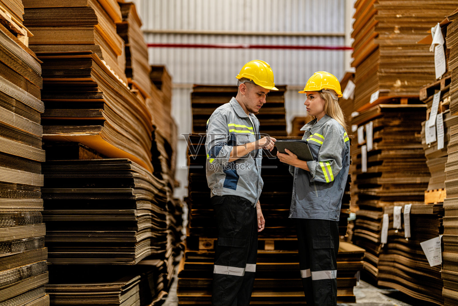 一男一女工人边走边检查货物，准备发货。女工视察商店工厂。物流员工在现场仓库区拿着文件夹准备运输。照片摄影图片