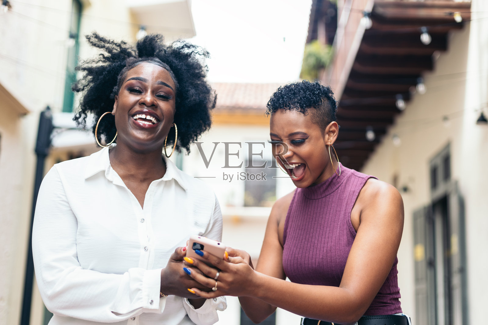 快乐的女性在城市中行走时使用手机照片摄影图片