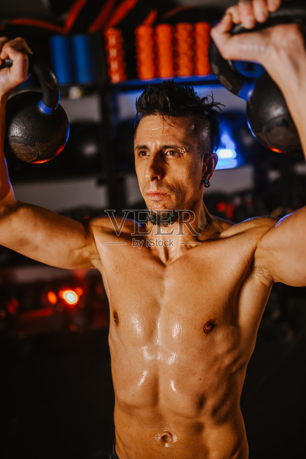 一个汗流浃背的男人在黑暗的现代健身房用壶铃锻炼照片摄影图片