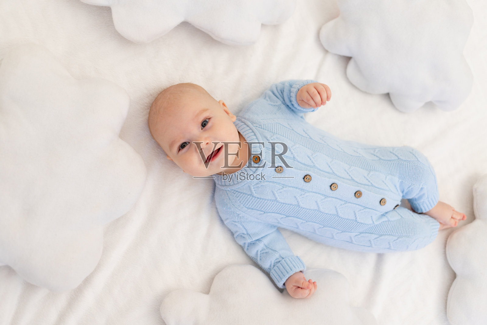 婴儿躺在床上，枕在云中。儿童纺织品和床上用品。照片摄影图片