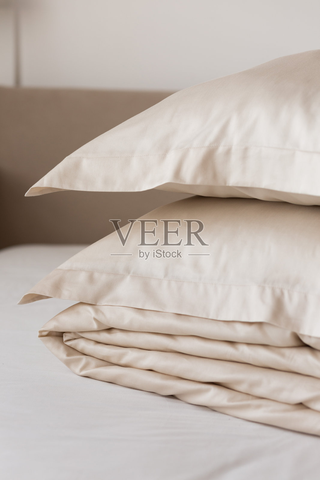 一叠米色缎面床上用品(缎面，莱赛尔，丝绸):羽绒被套和枕套在舒适的内部。温馨家居概念。家用纺织品照片摄影图片