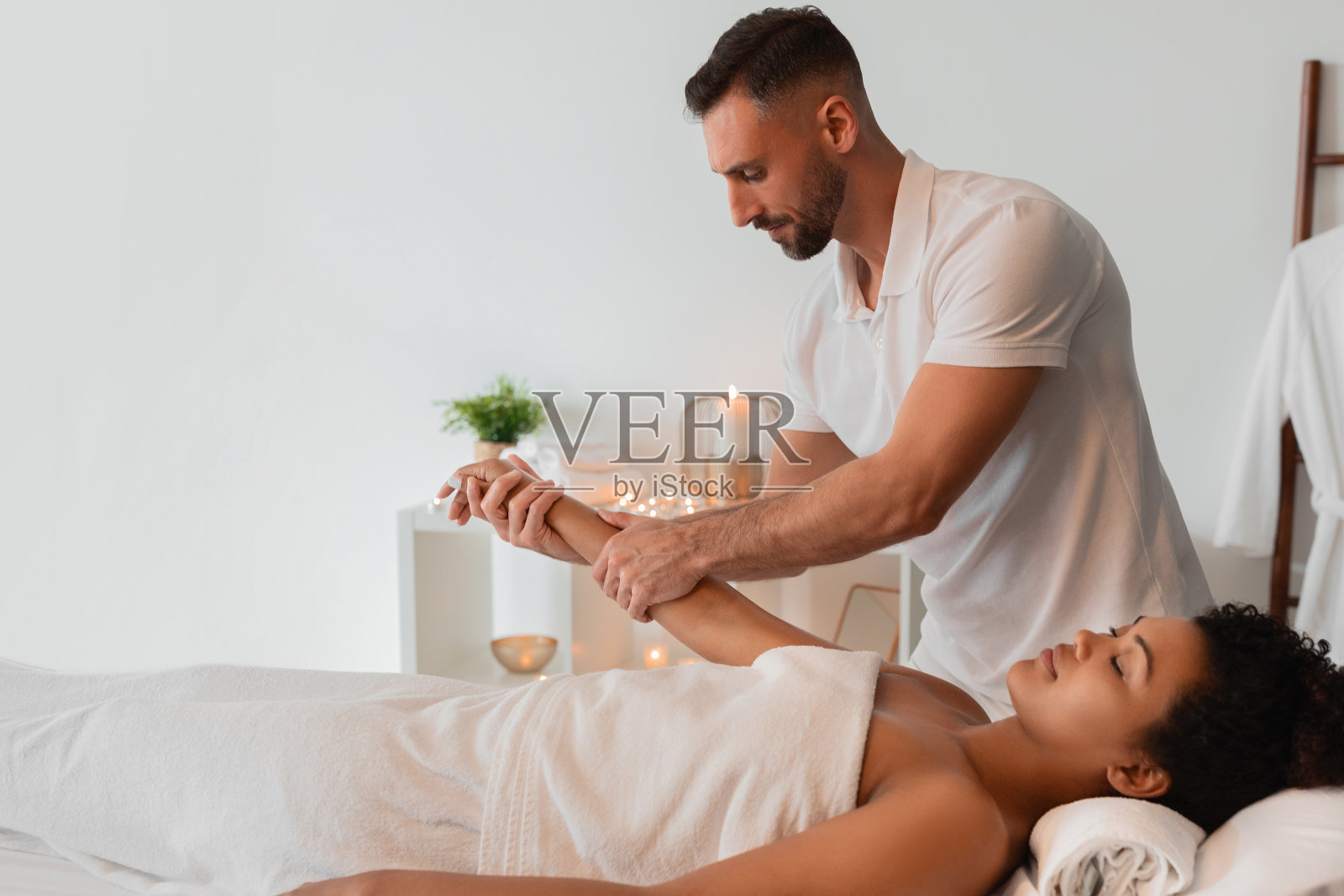 水疗按摩师轻轻地握着黑人女性的手臂照片摄影图片