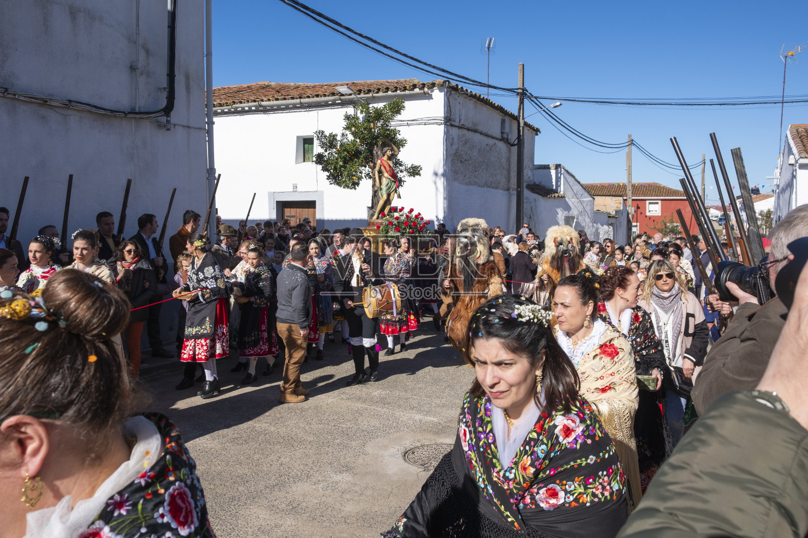 carantoñas节日期间，圣塞瓦斯蒂安的游行队伍穿过街道，伴随着在他们经过时开枪的男人和穿着传统服装的女人。照片摄影图片