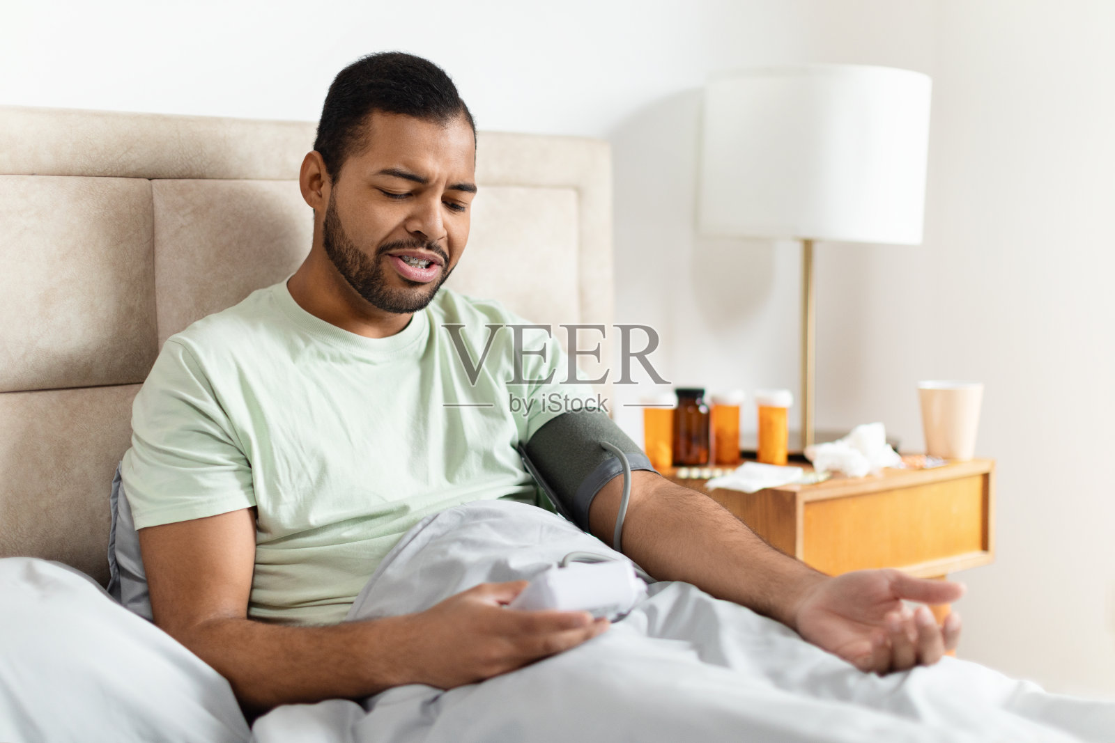 年轻人白天在卧室里测量血压照片摄影图片