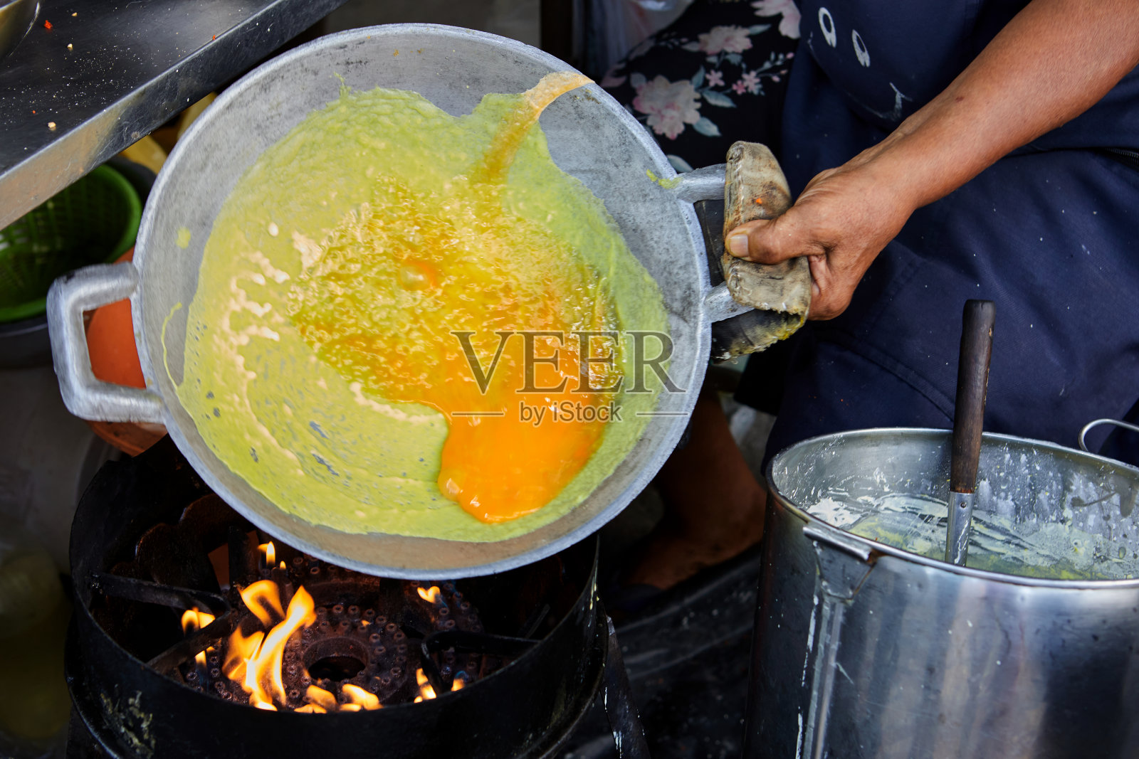 在街边小吃店，一名妇女在锅里煎着泰国风味的鸡蛋脆饼照片摄影图片