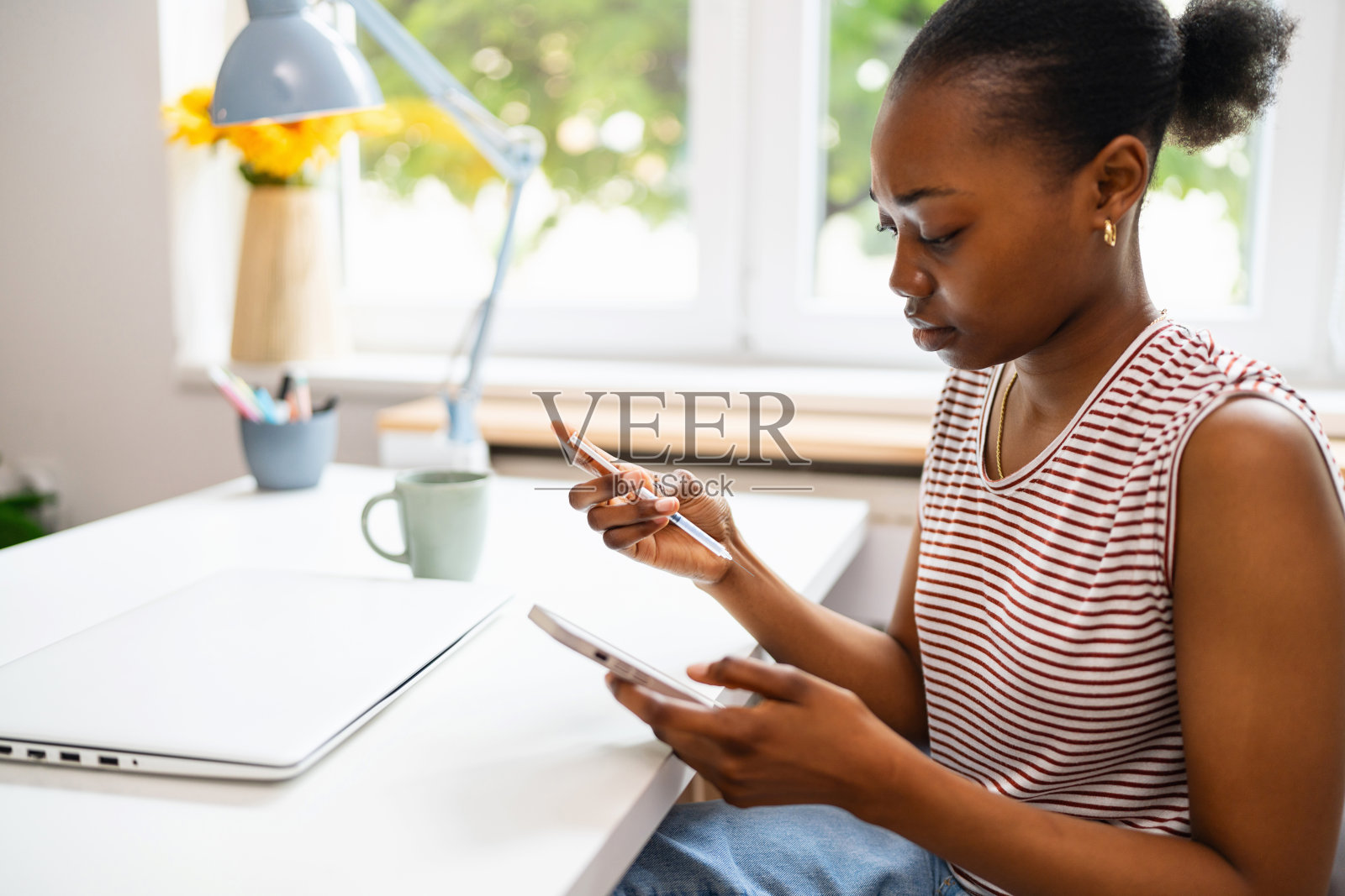 一名年轻女子在家办公室工作时，一边注射胰岛素一边使用智能手机照片摄影图片
