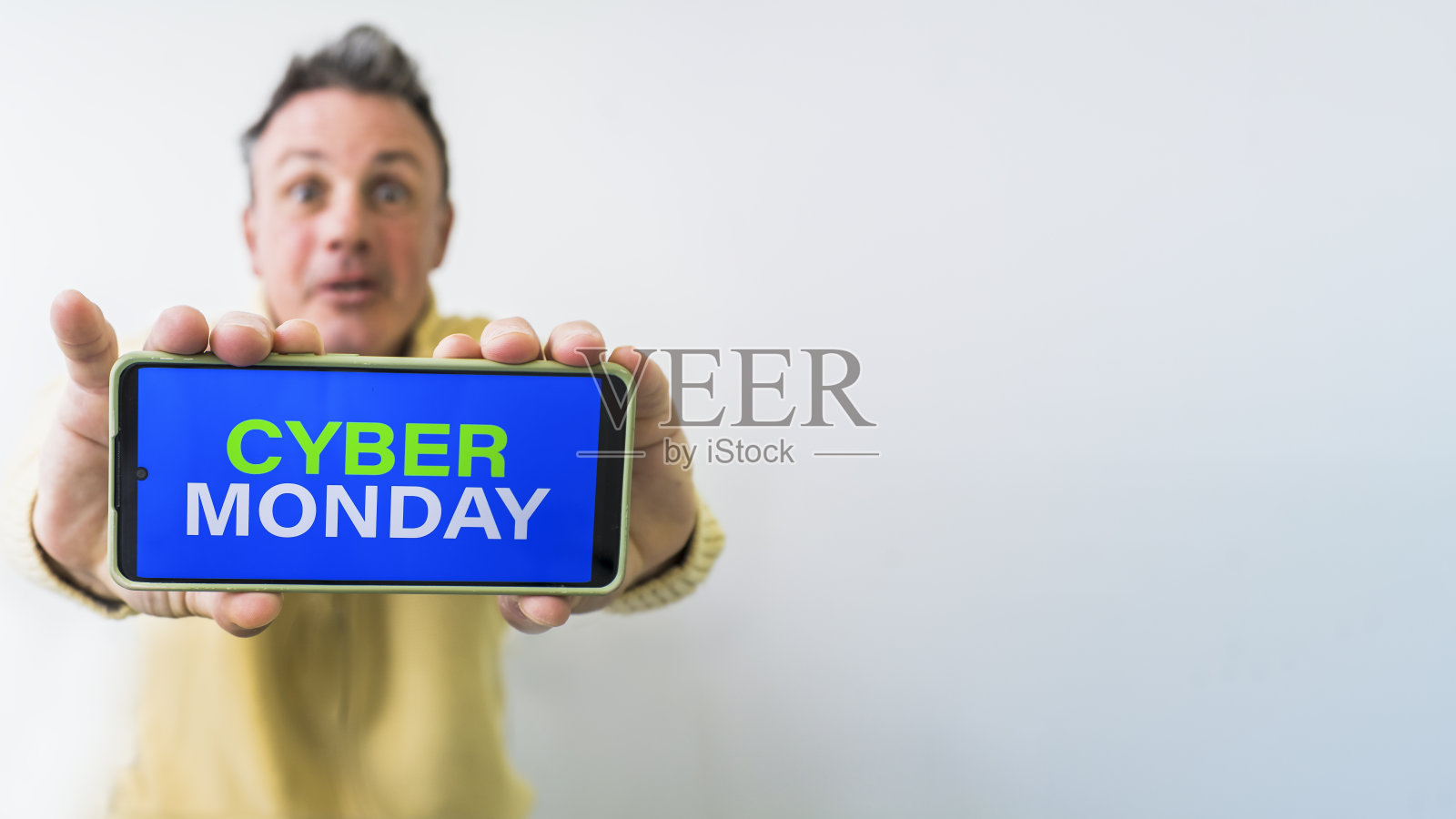 一个疯子拿着手机，屏幕上有网络星期一的广告。本空间照片摄影图片