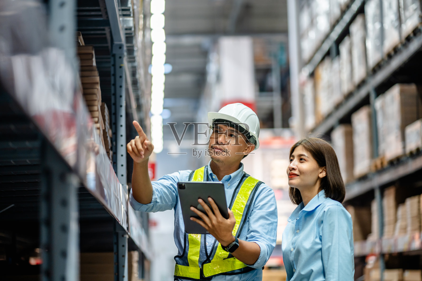仓库工作人员一起使用数字平板电脑查看大型仓库货架上的库存，智能仓库管理系统，供应链，物流网络技术概念照片摄影图片