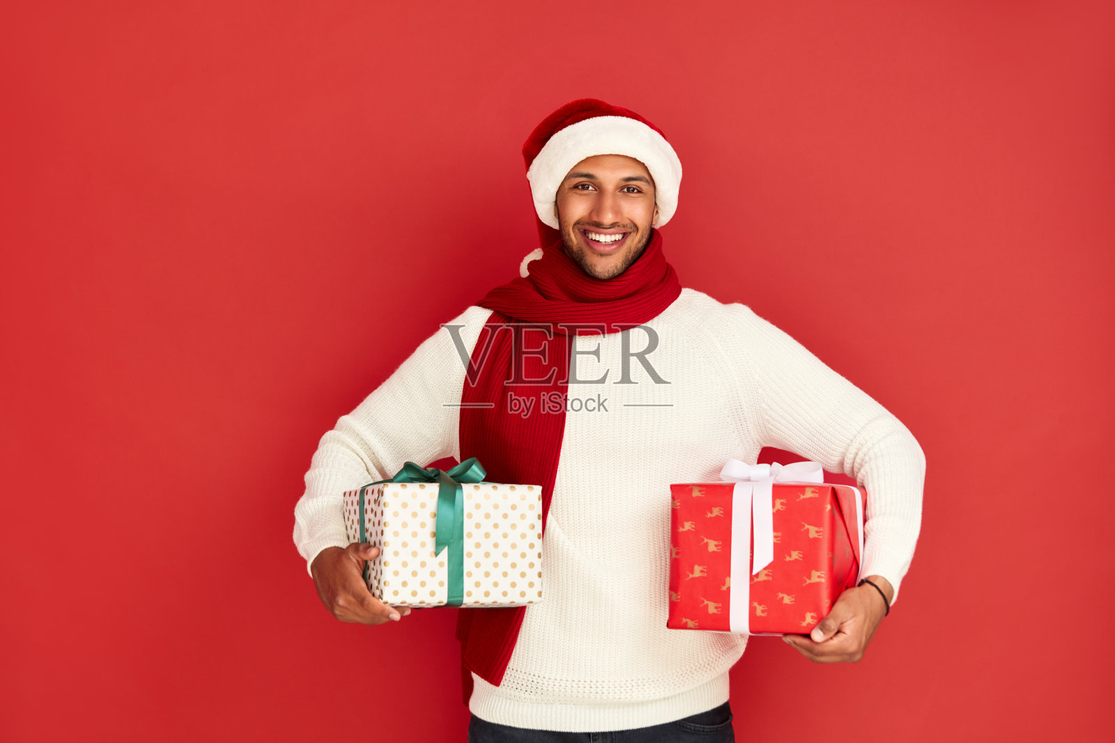 快乐的人拿着礼物。戴圣诞帽的混血儿拿着礼物盒照片摄影图片
