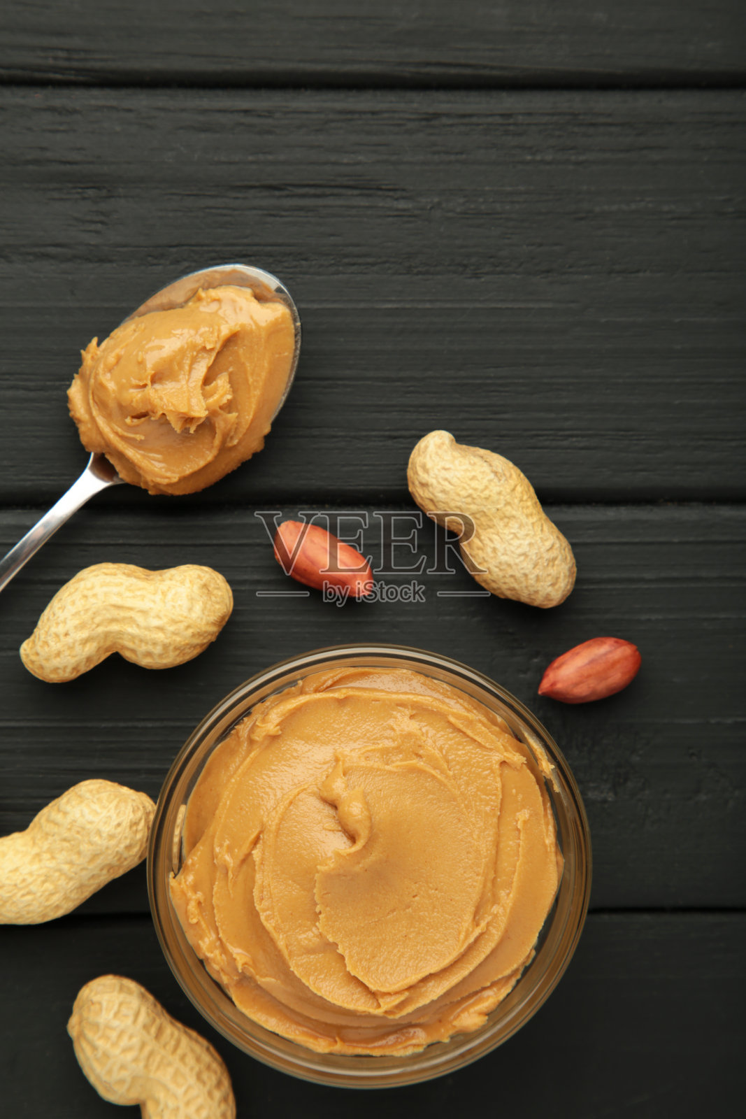 一碗花生酱和花生在黑色的木制背景。小碗里的奶油花生意面。照片摄影图片
