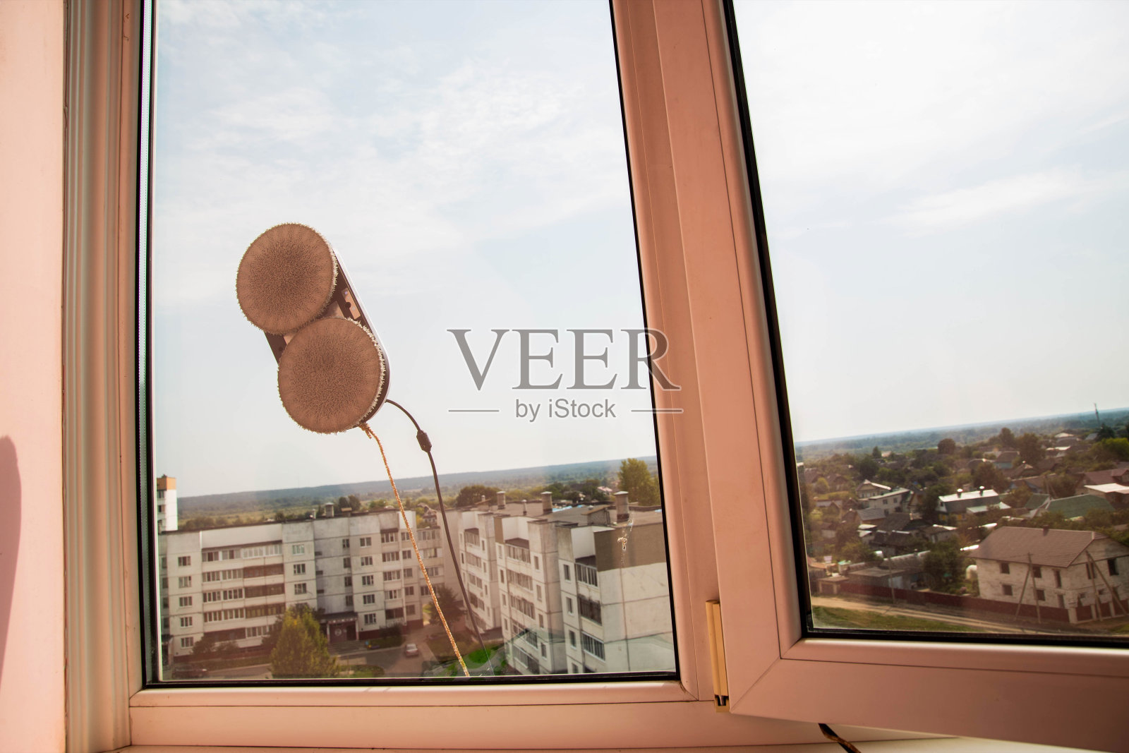 一个现代的真空机器人窗户清洁工清洗pvc阳台框架上的玻璃污垢和污渍。秋天的安全。文本复制空间照片摄影图片