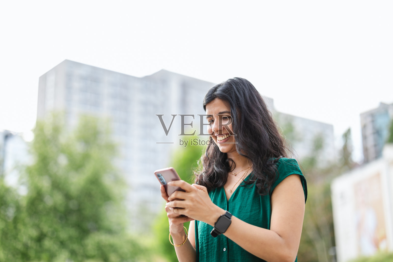 微笑的年轻女子在城市里使用她的智能手机照片摄影图片