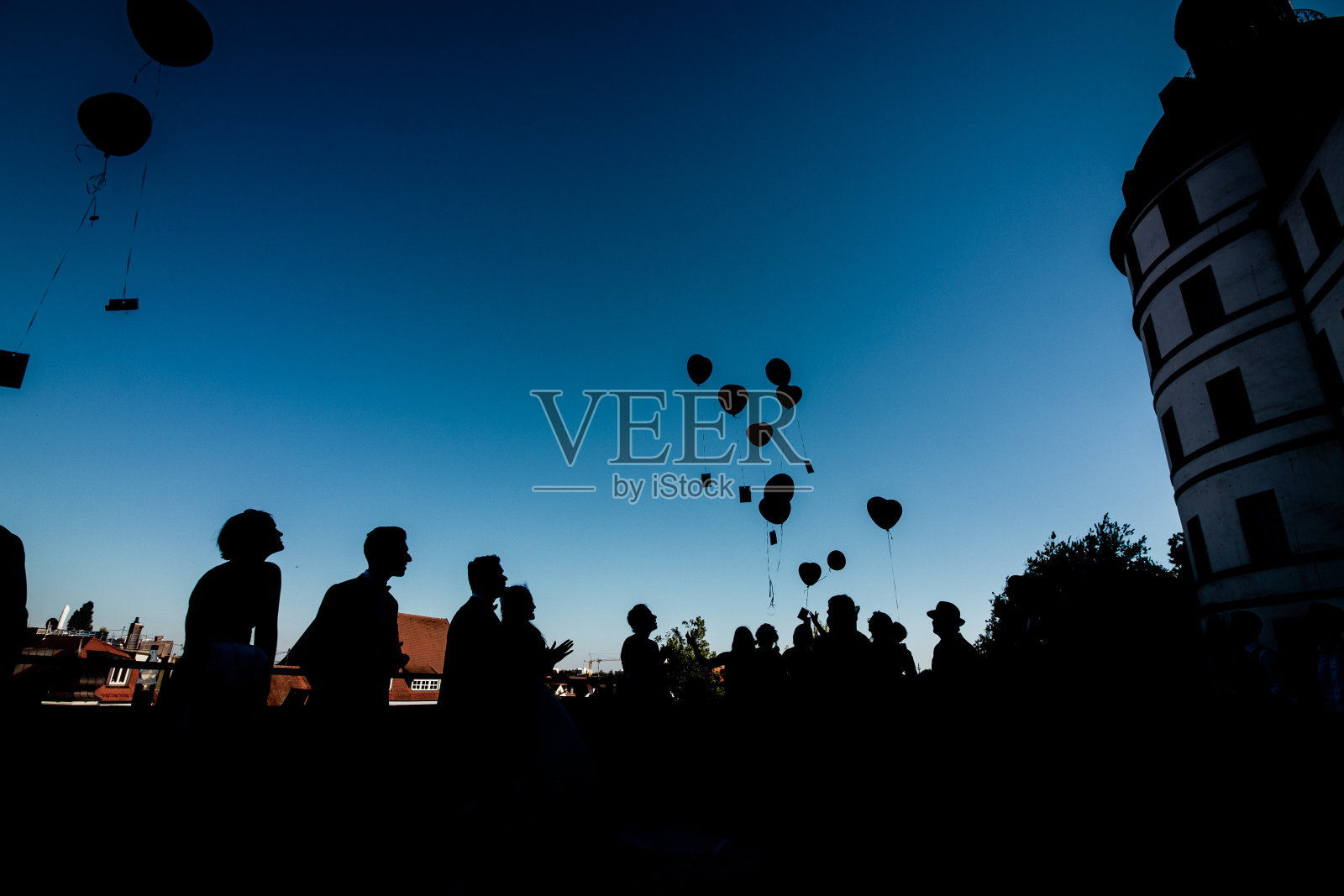 新人和他们的朋友在婚礼上的剪影像雨点一样洒满了气球照片摄影图片