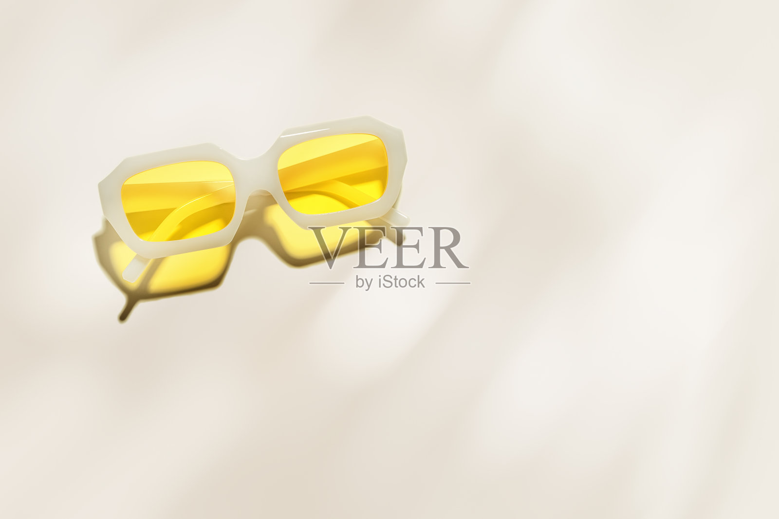 时尚的黄色太阳镜，米色背景上的透明黄色玻璃，阳光下的阴影和眩光，夏季时尚的白色塑料框眼镜。夏季促销概念，广告空间照片摄影图片