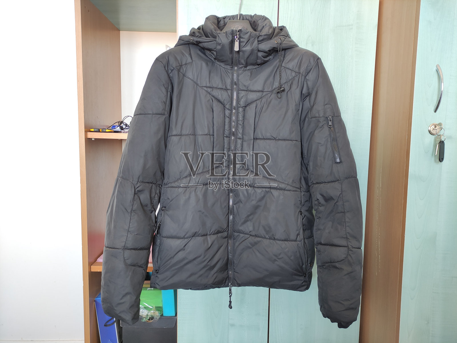 衣柜门上的衣架上挂着一件深色的冬季夹克照片摄影图片