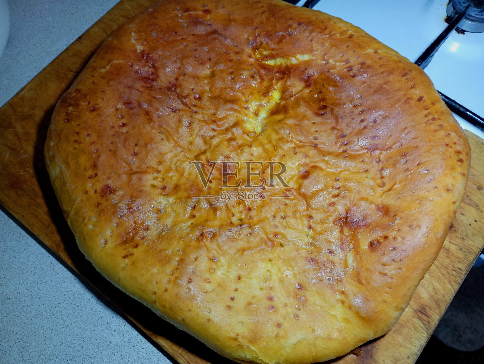 木质厨房板上美味的烤土豆派。美味的食物和它的准备在厨房的话题。在烤箱里煮的家常食物。照片摄影图片