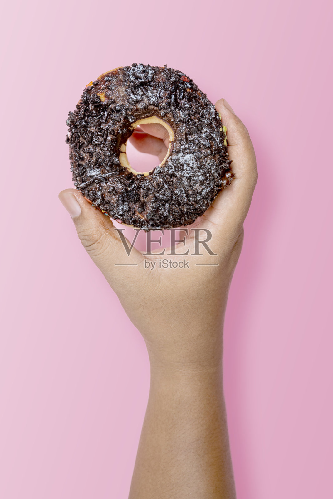 一只手拿着巧克力点缀的美味甜甜圈照片摄影图片