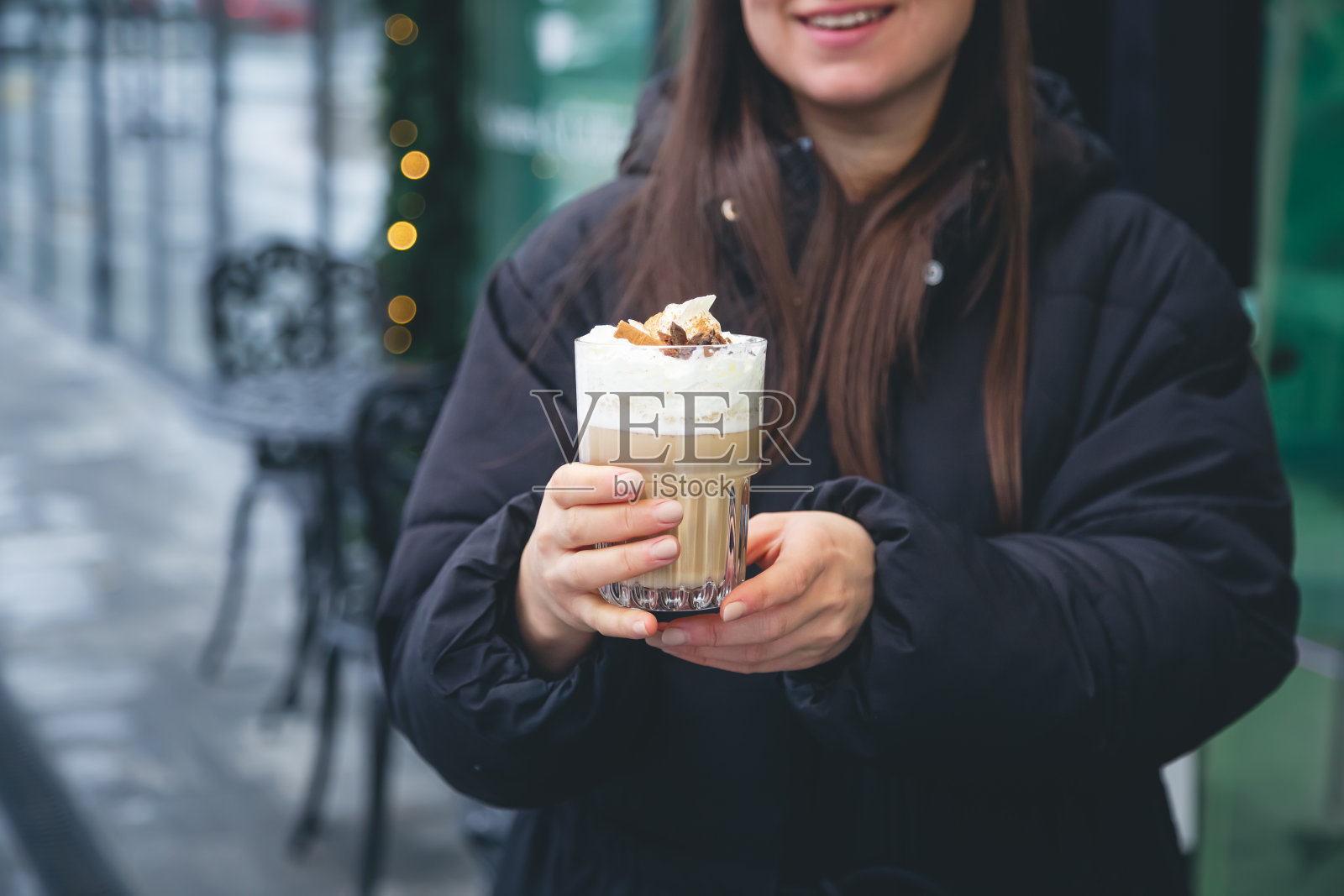 咖啡加奶油，肉桂和八角在外面的女性手中。照片摄影图片