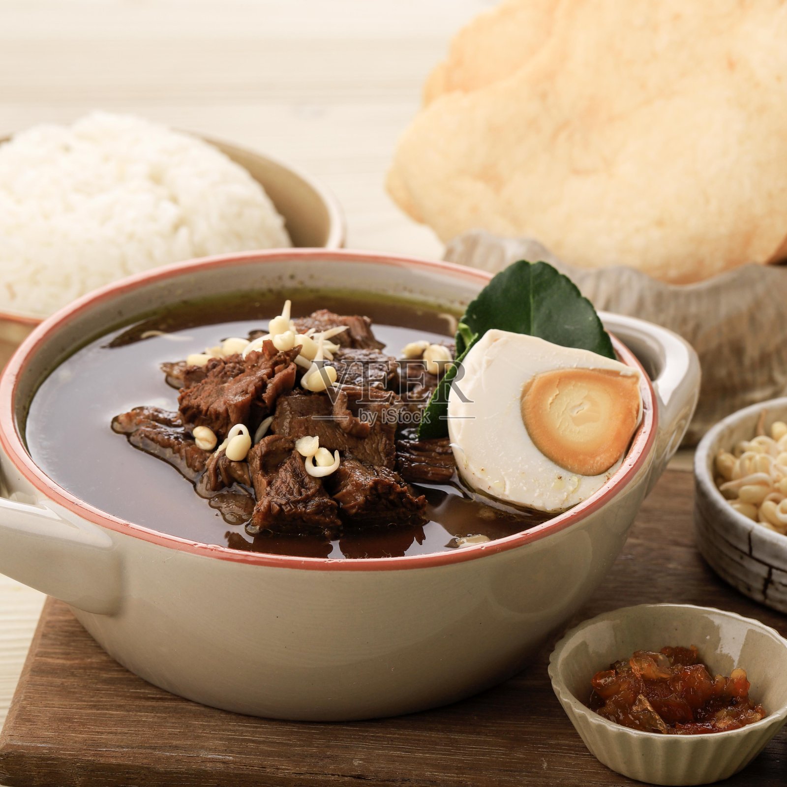 Rawon是一种黑牛肉汤，起源于印度尼西亚的东爪哇。配米饭和咸蛋。美味丰富的香料和传统的印尼草药。用陶瓷碗盛。照片摄影图片