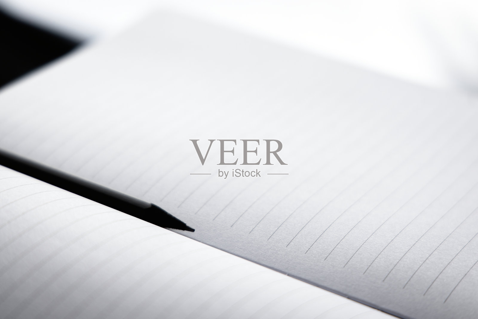 黑色的铅笔放在空白的笔记本上。照片摄影图片