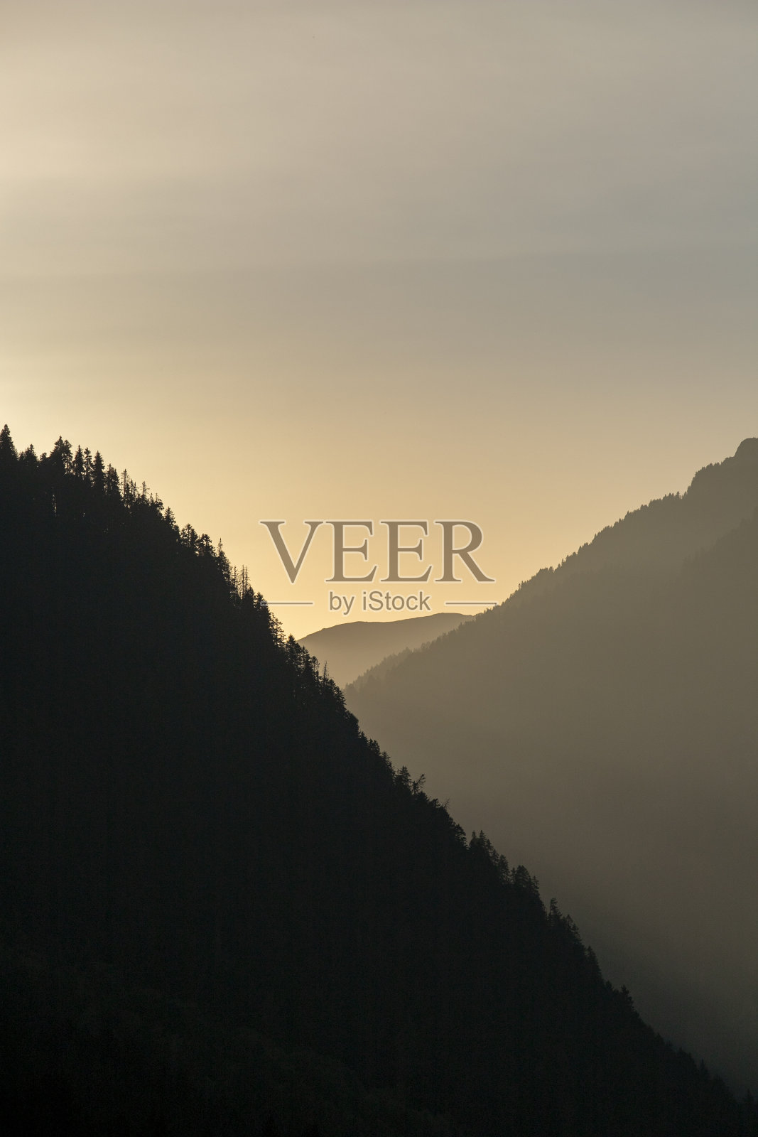 日落时的山影。两山之间的夕阳反射照片摄影图片