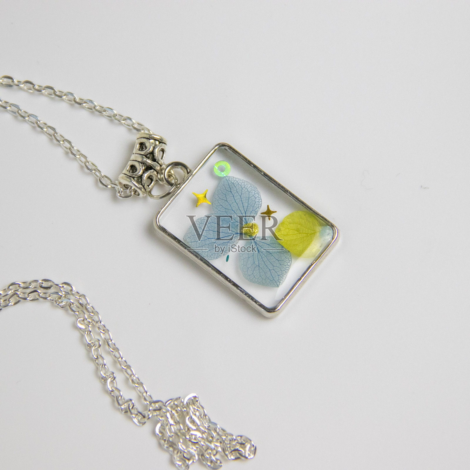 用环氧树脂和天然花朵制作的DIY服装首饰，DIY首饰大师。美丽的耳环和吊坠在家里制作的珠宝树脂。照片摄影图片