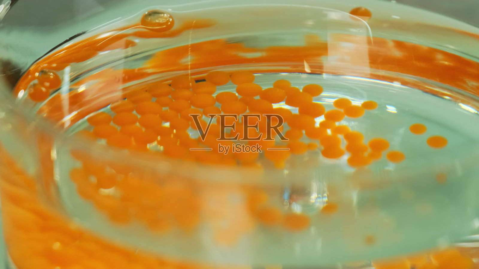 将有色混合物滴入有油液的玻璃中照片摄影图片