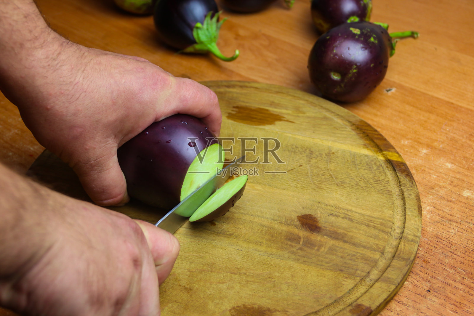 厨房切菜板上男性手切茄子的特写镜头照片摄影图片
