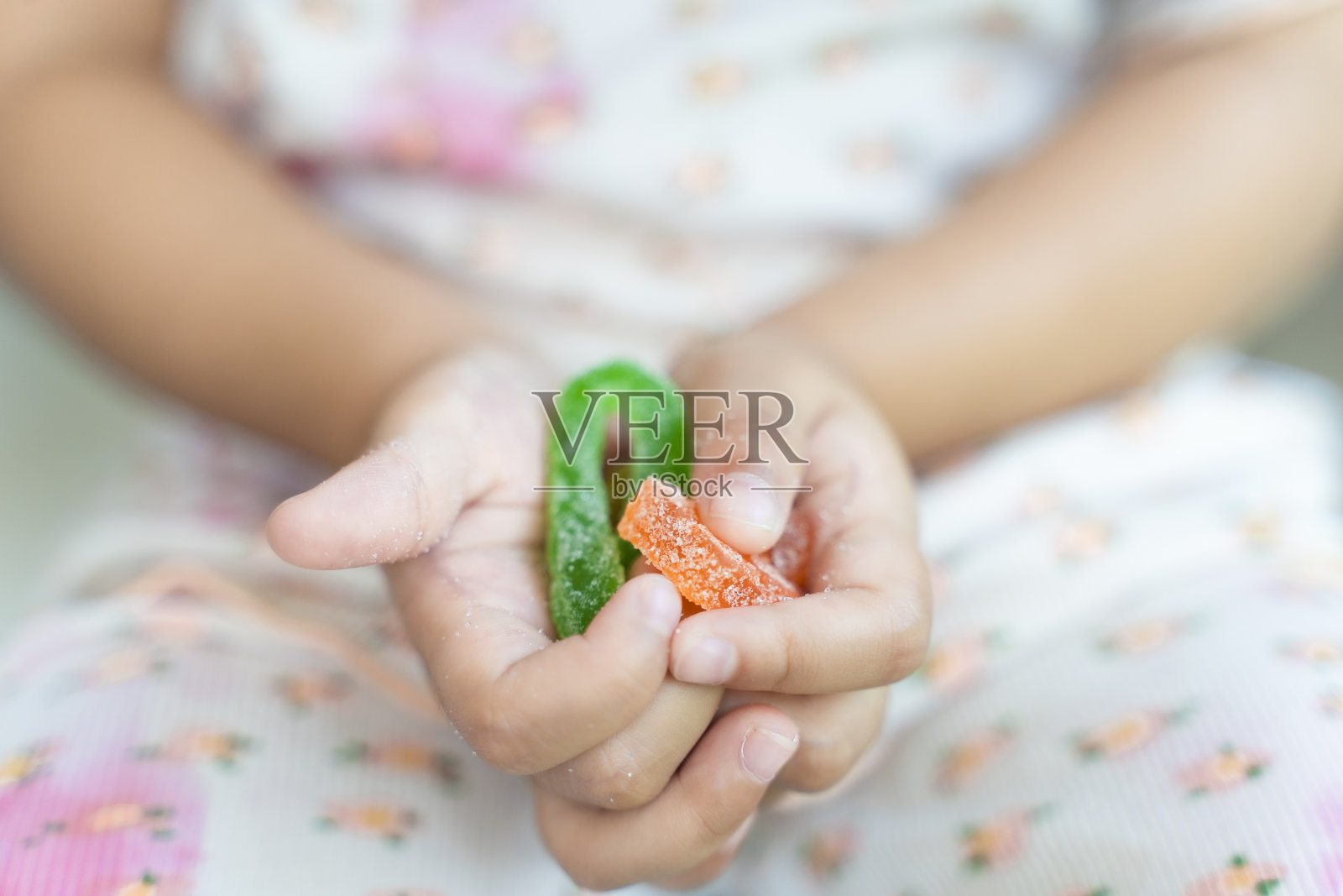 一个亚洲小孩的特写，3岁的小女孩手里拿着五颜六色的胶状糖果，果冻口香糖。照片摄影图片