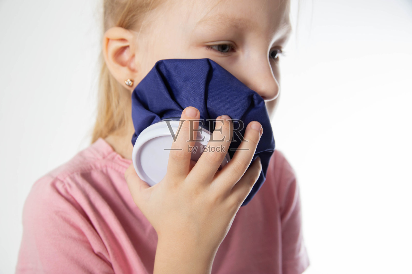 一个七岁的小女孩用冷敷敷她疼痛的牙齿。用冷的、近距离的镜头来缓解牙齿的炎症和疼痛。当地冷冻疗法照片摄影图片