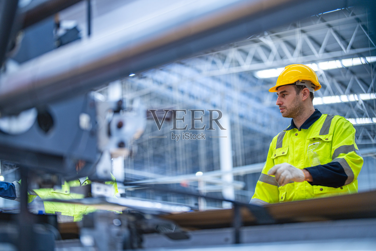 男女技术人员在重型机上检查工艺。机械工程队生产。工业制造业。工人拿着药片和文件夹。高科技生产。照片摄影图片