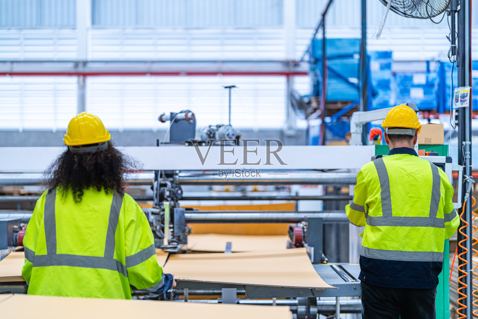 男女技术人员在重型机上检查工艺。机械工程队生产。工业制造业。工人拿着药片和文件夹。高科技生产。照片摄影图片