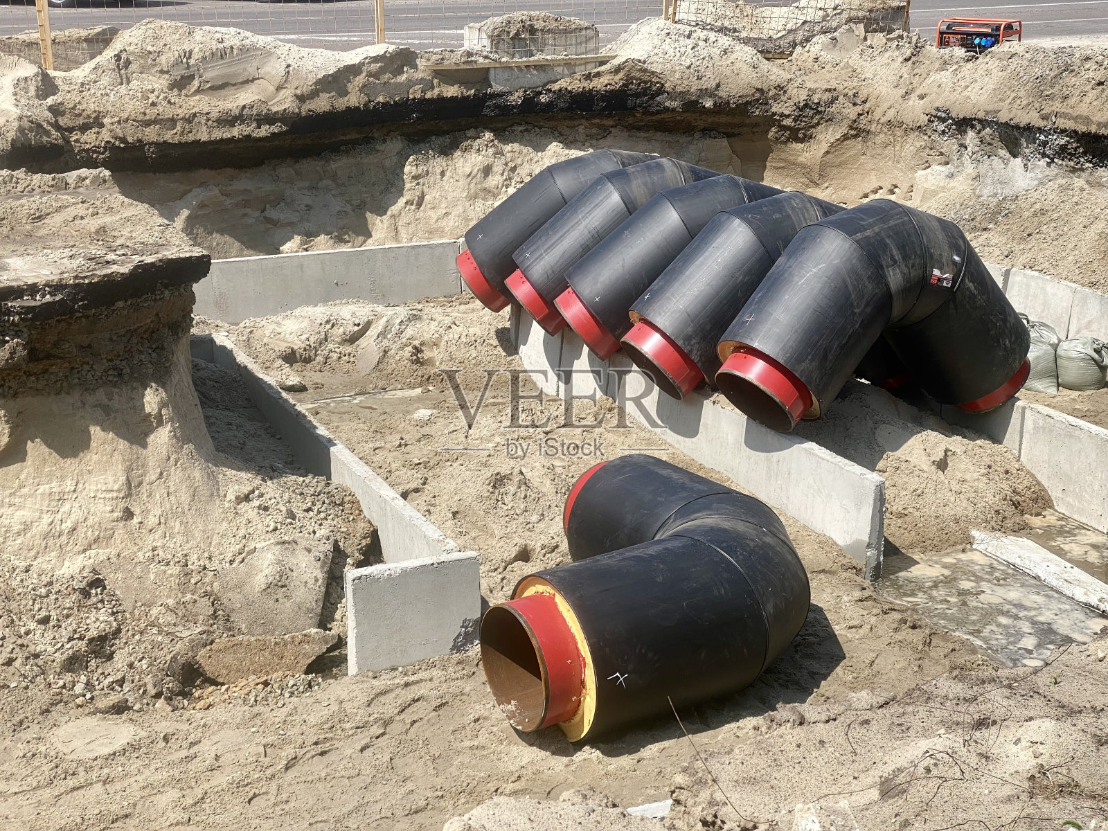 建筑行业。建筑商正在为一个新的住宅区铺设供热管道。套管内供热管道的弯曲。加热系统故障。照片摄影图片