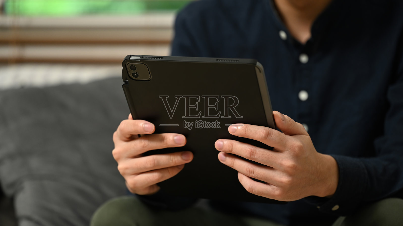 裁剪镜头的男子看视频的数字平板电脑和放松在沙发上的客厅照片摄影图片