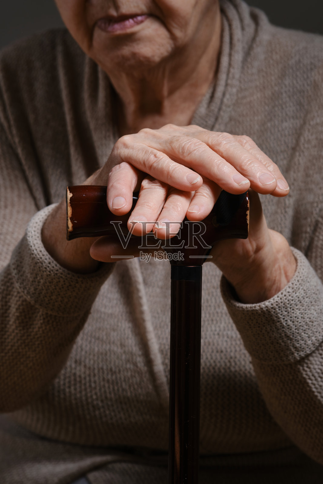 一位老妇人的手握着手杖柄。照片摄影图片